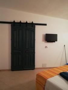 圣彼得罗镇Al 101...sogni...的卧室设有黑色的门,墙上配有电视。