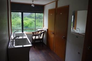 草津Kusatsu Onsen Guesthouse Gyoten的一间带水槽的浴室和一个带椅子的窗户