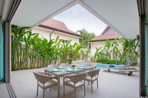 拉威海滩Villa Karina的一个带桌椅的庭院和一个游泳池