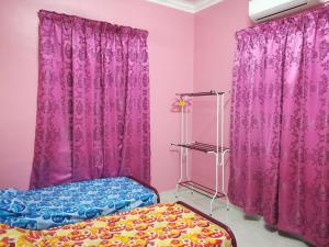瓜拉丁加奴HOMESTAY DAMAI YUSMILA的粉红色的客房配有一张床和紫色窗帘