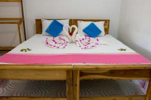 阿鲁甘湾Beach Lagoon Parans的一张带粉红色和蓝色枕头及弓的床铺