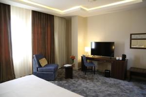多哈多哈城市酒店的酒店客房配有一张床和一张书桌及一台电视