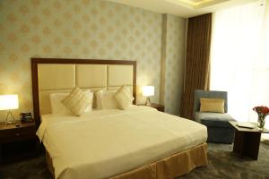 多哈多哈城市酒店的卧室配有一张白色大床和一把椅子