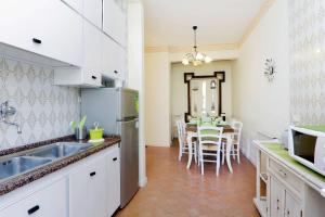 罗马马卢奇尼公寓的厨房配有白色橱柜和桌椅