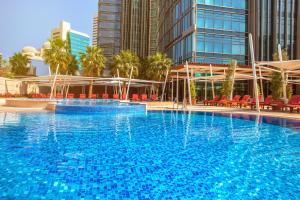 多哈多哈罗塔纳城市中心酒店的一座大型蓝色游泳池,配有红色椅子和建筑