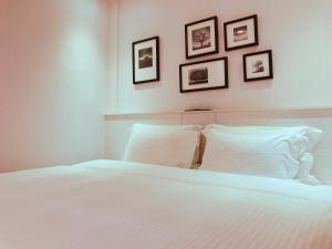 屏东县薇米文旅的卧室配有一张白色床,墙上挂有三张照片