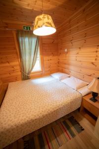 SulkavaHoliday Village Kukkapää的木制客房内的一间卧室,配有一张床