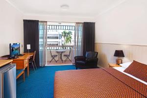 汤斯维尔城市绿洲酒店的酒店客房设有一张床、一张书桌和一个阳台。