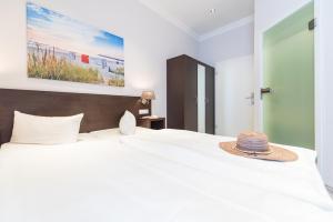 宾茨Hotel Villa Belvedere的一间卧室配有一张白色大床,上面有帽子