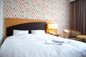 苫小牧市苫小牧永安国际酒店的卧室配有白色的床和带台灯的桌子