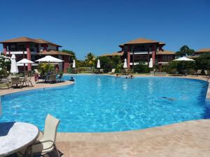 普拉亚多PRAIA DO FORTE - CONDOMINIO VILLAGE DAS ACACIAS - PISCINAS NATURAIS的一个带桌椅的大型蓝色游泳池