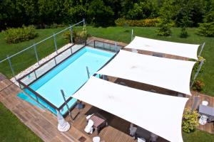 Belforte del ChientiChiaroscuro的享有带两把白色遮阳伞的游泳池的顶部景致
