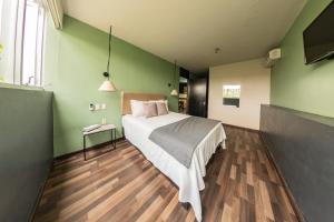 奥里萨巴卢西塔尼亚套房公寓式酒店的一间卧室设有床铺和绿色的墙壁