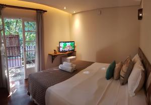 坎布里Pousada Camburi的卧室配有一张大床,墙上配有电视