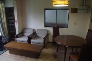 草津Kusatsu Onsen Guesthouse Gyoten的一间带桌子和两把椅子的客厅、一张桌子以及一间用餐室。