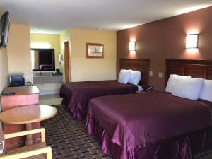 IndianolaAmericas Best Value Inn-Indianola的酒店客房设有两张床和一张桌子。