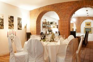 格明德Hotel & Restaurant Stern的一间设有白色桌椅的用餐室和砖墙