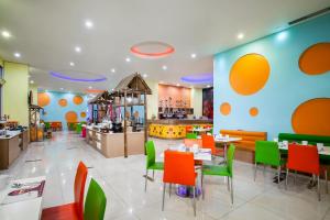 梭罗favehotel Manahan - Solo的一间设有橙色和绿色椅子及桌子的餐厅
