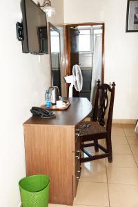 内罗毕Jamia Central Hotel的客房设有一张桌子、一把椅子和一台电视。