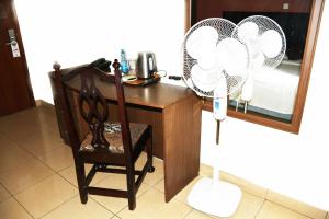 内罗毕Jamia Central Hotel的客房设有带风扇和椅子的书桌。