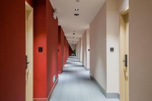 苏州沛喜酒店苏州观前街店的一条走廊,有红色和白色的墙壁和长长的走廊