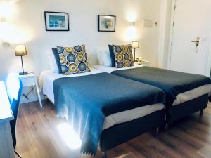 科英布拉科英布拉植物园酒店的一间卧室配有两张带蓝色毯子和枕头的床