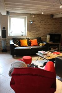 勒韦尔努瓦Gite Le Meix Chapeau的客厅配有黑色沙发和橙色枕头。