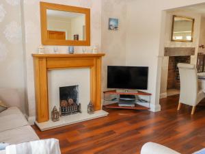 科尔温湾Penrhyn View的一间带电视和壁炉的客厅