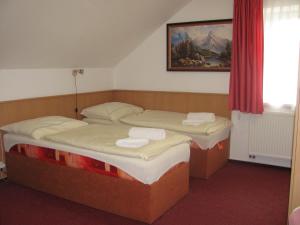 KrmelínŠindlerův Dvůr的配有红色窗帘的客房内的两张单人床