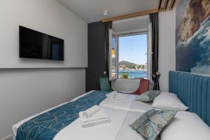 杜布罗夫尼克Apartments and Rooms Villa Naida的酒店客房设有一张带大窗户的床。