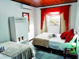 伊瓜苏Gardenia House的一间卧室设有两张床,窗户配有红色窗帘