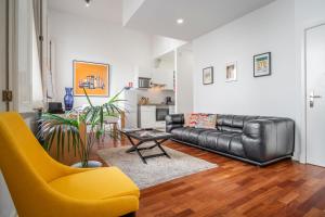 里斯本查多 - CH街LV尊贵公寓的客厅配有真皮沙发和黄椅