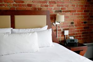 蒙特利尔内利冈酒店的卧室配有白色的床和砖墙
