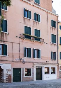 威尼斯Prince Apartments的粉红色的建筑,设有窗户和阳台