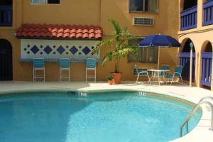 基西米Sevilla Inn Kissimmee- Near Disney的一个带椅子和桌子的游泳池以及一把遮阳伞