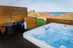 邓巴贝斯韦尔公园酒店 的甲板上的热水浴池,配有桌子和大海