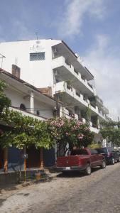 巴亚尔塔港Casa del Parque Vallarta的停在白色建筑前的一辆红色卡车