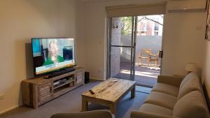 阿德莱德North Adelaide Apartment的客厅配有电视、沙发和桌子
