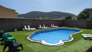 菲尼斯特雷Hotel Rústico Prado da Viña的一个带椅子和围栏的庭院内的游泳池