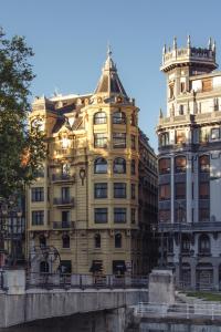 毕尔巴鄂Hotel Tayko Bilbao的一座大型黄色建筑,毗邻一座高大的建筑