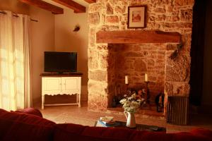 福梅尔La Grange dans la Foret的客厅设有石制壁炉和电视。