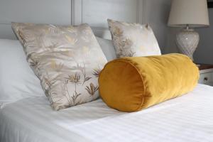 布什米尔斯考斯威酒店的床上的黄色枕头和两个枕头