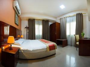 马斯喀特Safeer Plaza Hotel的一间卧室配有一张床、一张书桌和一台电视。