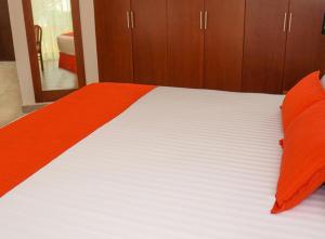 比亚埃尔莫萨维瓦维拉尔莫萨酒店的一张配有橙色和白色床单及木制橱柜的床