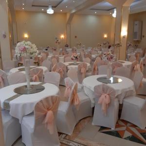 阿尔及尔Numidien Hotel的宴会厅配有白色的桌椅和粉红色的弓