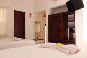 埃斯孔迪多港Hotel Barlovento的一间卧室配有两张带白色床单的床和电视。