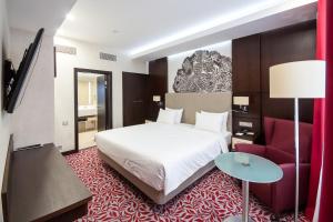 乌法巴施克瑞亚酒店的酒店客房,配有一张床和一张红色椅子
