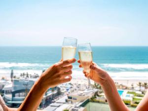 黄金海岸诺富特冲浪者天堂酒店的两人在海滩前戴香槟杯