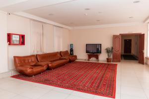 塔什干GYM Inn的客厅里一张棕色的皮沙发,有红色地毯