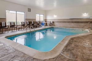 堪萨斯城堪萨斯城赛道康福特套房酒店的游泳池位于酒店客房内,配有椅子和桌子